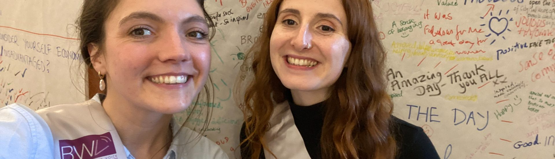 Two women smiling in front of a board